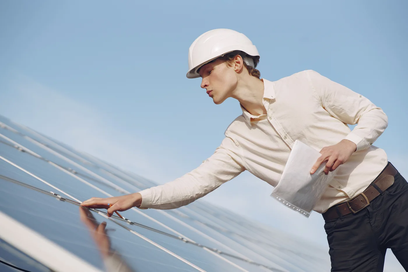 Worker washing dust and debris from the surface of a solar panel